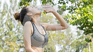 Asian cute sport healthy fit and firm slim teen girl drink water from plastic bottle on the hand in summer hot day at outdoor