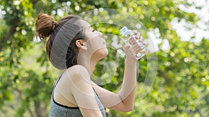 Asian cute sport healthy fit and firm slim teen girl drink water from plastic bottle on the hand in summer hot day at outdoor