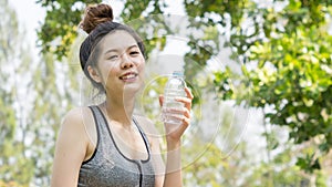 Asian cute sport healthy fit and firm slim teen lady hold plastic bottle of water on the hand in summer hot day at outdoor garden.