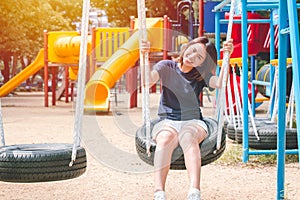 Asian cute teen happy smile sitting at swing kid playground park, leisure young innocent girl