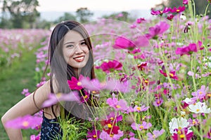 Asian cute young woman joyful, smiling with pink cosmos background