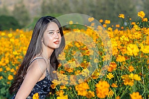 Asian cute young woman joyful, smiling with yellow cosmos background