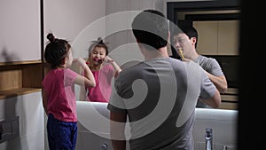 Asian dad and daughter brushing teeth in bathroom