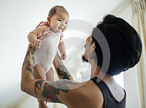 Asian dad holding his baby up with love