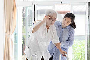 Asian daughter or care assistant helping support senior woman or mother,communicates the symptoms of vertigo;dizziness;migraine; photo