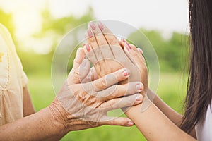 Asian daughter greeting or pay respect to her mother, two hands holding each others