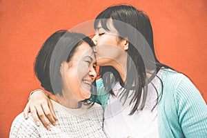 Asian daughter kissing mum on mother day - Happy family people enjoying time togehter - Love, motherhood lifestyle, tender moments photo