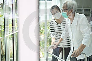 Asian daughter take care of senior mother,elderly woman is looking outside through window feeling bored,depressed,stressed,life