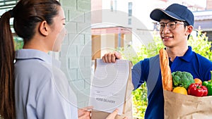Asian deliver man in uniform handling bag of food vegetables and greens to customer at door home, food delivery concept
