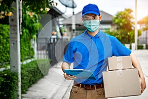 Asian delivery man in blue t-shirt carrying parcel box and document to sign