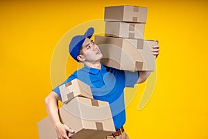 Asian delivery man in blue t-shirt send parcel box to customer isolated on yellow background