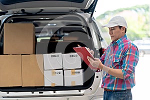 Asian Delivery Man checking list on clipboard near a Car