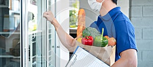 Asian delivery man holding grocery bag of food, fruit, vegetable and invoice clipboard during knocking