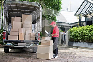 Asian delivery man in red uniform delivering parcel boxes to woman recipient at home