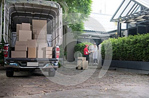 Asian delivery man in red uniform delivering parcel boxes to woman recipient at home