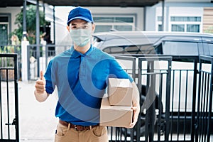 Asian Delivery man wearing mask send a package carton thumb up on front receiver shipping deliver