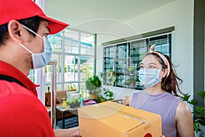 Asian delivery servicemen wearing a red uniform with a red cap and face mask handling cardboard boxes to give to the female