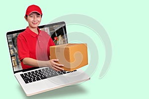 Asian delivery woman in red shirt with blur warehouse background, holding goods order in package parcel out from laptop computer