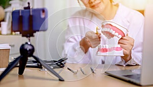 Asian dentist woman working online at home. Recording blog video for tutorial instructional brushing teeth clean. Dentistry and photo