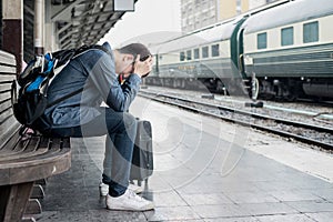 Asian depressed traveler waiting at train station after mistakes photo