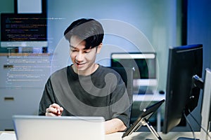 Asian developer writing code at night in modern office setup. Concept of software engineering, programming, digital workspace