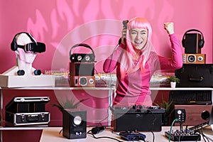 Asian dj with pink hair mixing techno music with eletronic having fun in club during night time