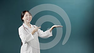 An asian doctor with black hair in a medical gown is posing, standing with a thumbs up and looking at the camera