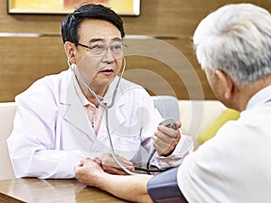 Asian doctor checking blood pressure of a senior patient