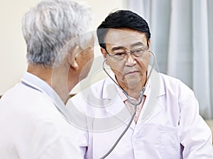 Asian doctor checking a senior patient