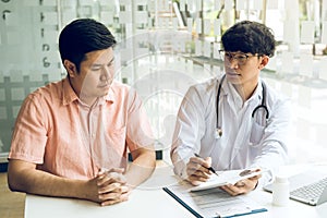 Asian doctor is examining the abnormal items of the body and diagnosing the disease in the paper with the medical report of the