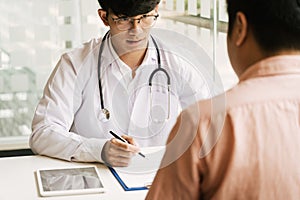 Asian doctor is examining the abnormal items of the body and diagnosing the disease in the paper with the medical report of the