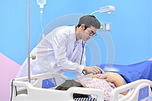 Asian doctor examining pregnant woman with stethoscope