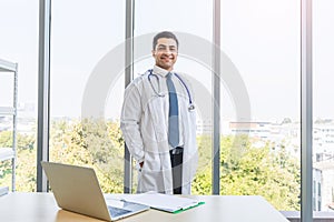 Asian doctor in gown uniform working with happiness smiling at hospital or medical clinic