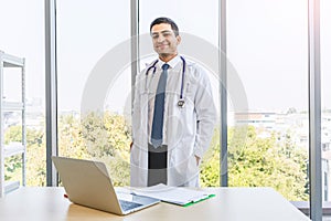 Asian doctor in gown uniform working with happiness smiling at hospital or medical clinic