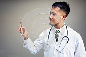 Asian doctor holding injection syringe on gray background