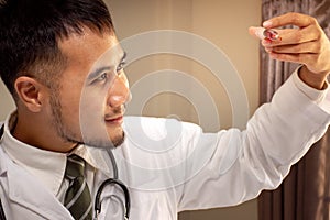 Asian doctor holding injection syringe on gray background