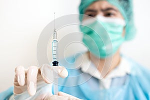 Asian doctor holding medical syringe,preparing a vaccine or a serum for injection to a patient,treatment with a vaccine to produce