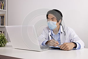 Asian Doctor and Stethoscope Wear Face Mask Write Experimental Results Report and Using Laptop Computer