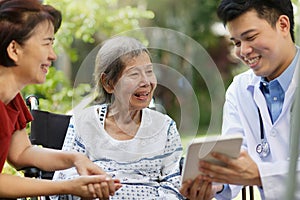 Asian doctor talking with elderly female patient.