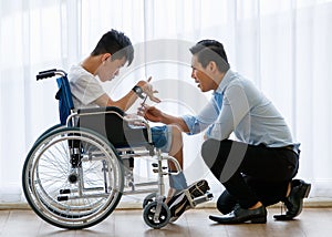 Asian doctor talking, support, and encouragement to a young disabled boy in a wheelchair