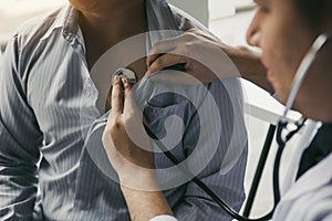 Asian doctor is using a stethoscope listen to the heartbeat of the elderly patient