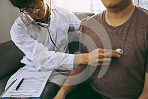 Asian doctor is using a stethoscope listen to the heartbeat of the elderly patient