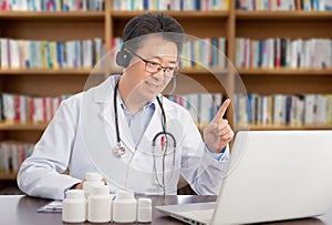 An Asian doctor who is remotely consulting with a patient. Telehealth concept