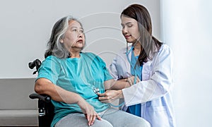 Asian doctor woman Using a stethoscope Listen to abdomen of elderly woman patients