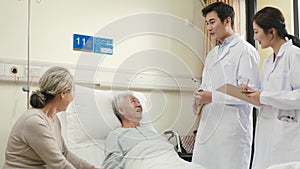 Asian doctors examine senior patient in hospital ward