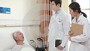 asian doctors informing senior patient of medical condition in hospital ward