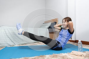 Asian doing home fitness and yoga on a fitness mat doing exercise at modern home in living room, sporty girl health care workout