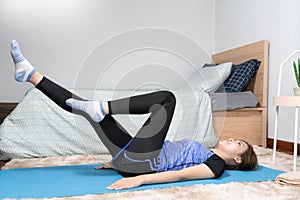 Asian doing home fitness and yoga on a fitness mat doing exercise at modern home in living room, sporty girl health care workout