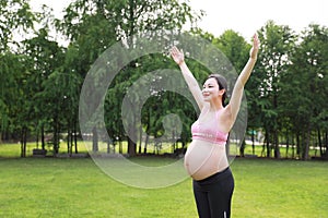 Asian Eastern Chinese happy beautiful pregnant woman hug embrace nature in green forest outdoor relaxed peaceful life