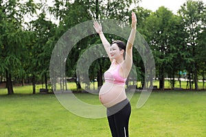 Asian Eastern Chinese happy beautiful pregnant woman hug embrace nature in green forest outdoor relaxed peaceful life